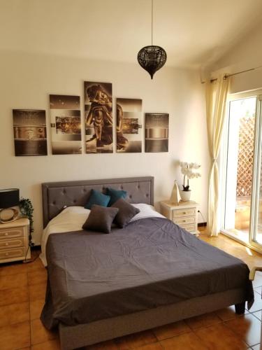 ein Schlafzimmer mit einem großen Bett mit Plakaten an der Wand in der Unterkunft Belle villa classée 4 étoiles proche plage avec jardin in Saint Cyprien Plage
