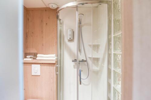 a shower in a bathroom with a glass door at Logis Auberge du Relais in Berenx