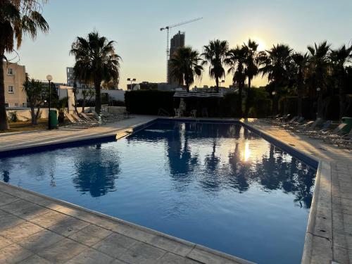 a large swimming pool with palm trees and chairs at Green Door Getaway in Limassol