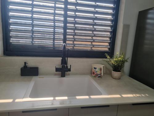 a white sink in a kitchen with a window at עלות השחר - יחידת אירוח בצפון in Qiryat Shemona