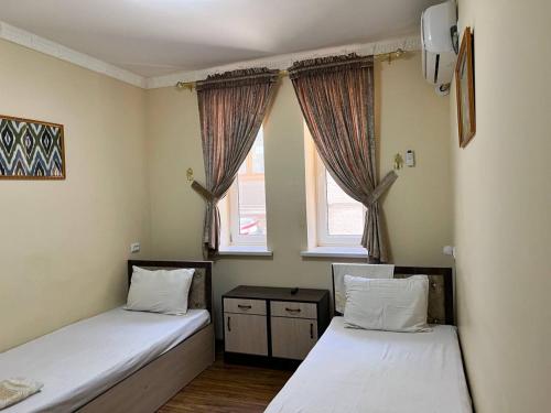 2 Betten in einem Zimmer mit 2 Fenstern in der Unterkunft Ikat Terrace in Buxoro