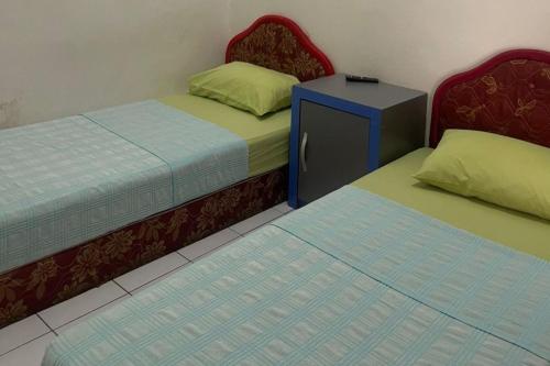 dos camas sentadas una al lado de la otra en una habitación en OYO 92924 Kalista Guest House Syariah, en Pekanbaru