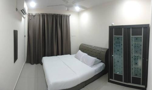 1 dormitorio con cama blanca y armario negro en KITAKAYA Homestay Kota Bharu - 8 Pax, en Kota Bharu