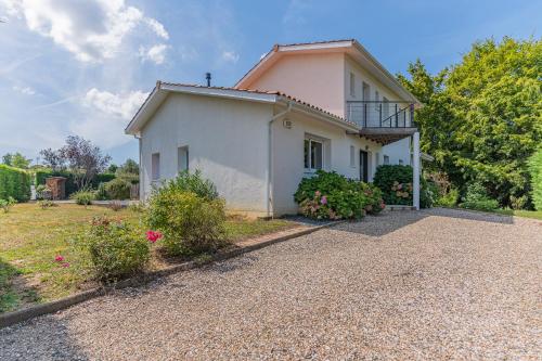 a white house with a balcony on a gravel driveway at Villa Saint-Martin - Pompignac in Pompignac