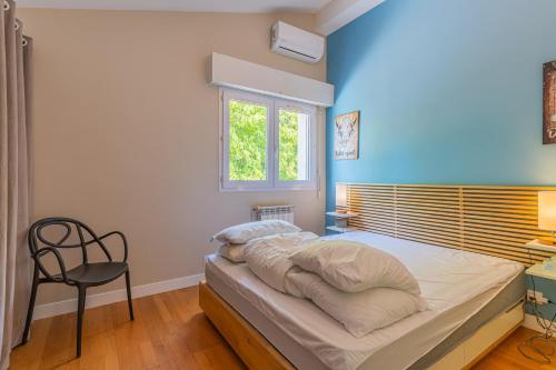 een slaapkamer met een bed met een stoel en een raam bij Villa St Martin in Pompignac