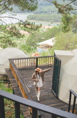 a woman walking down a wooden stairs next to a tent at Lavender Dalat Hotel and Resorts in Da Lat