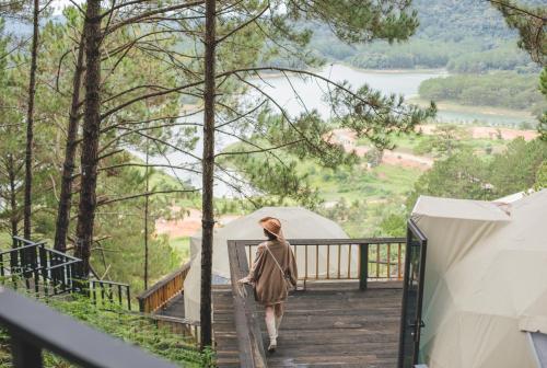 a woman walking down a wooden walkway with tents at Lavender Dalat Hotel and Resorts in Da Lat
