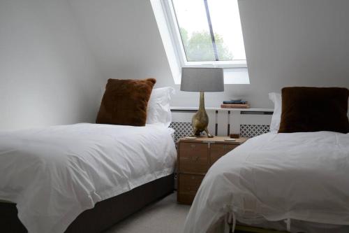 - une chambre avec 2 lits et une lampe sur une table de chevet dans l'établissement Luxury Barn near Soho Farmhouse, à Middle Barton