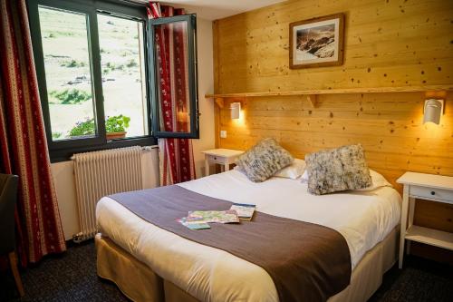 een slaapkamer met een bed in een kamer met houten wanden bij Hotel Le Faranchin in Villar-dʼArène