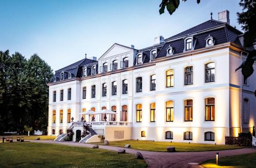 a large white building with a fountain in front of it at Weissenhaus Private Nature Luxury Resort in Weißenhaus