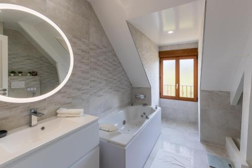 uma casa de banho com uma banheira, um lavatório e um espelho. em La Petite Chalautrière - Avec grand jardin 