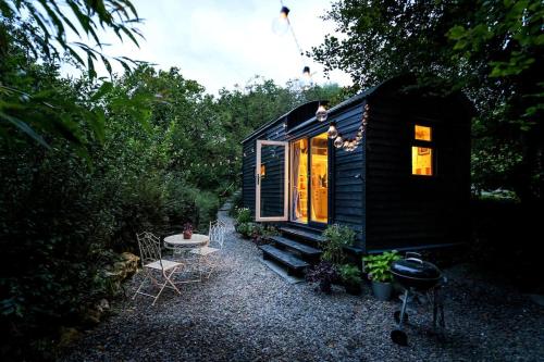 uma pequena casa preta minúscula com uma mesa e cadeiras em Fleur de Grog - Shepherds Hut em Bodmin