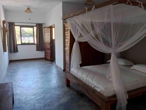 - une chambre avec un lit à baldaquin dans l'établissement MAISON CARREE, à Andilana
