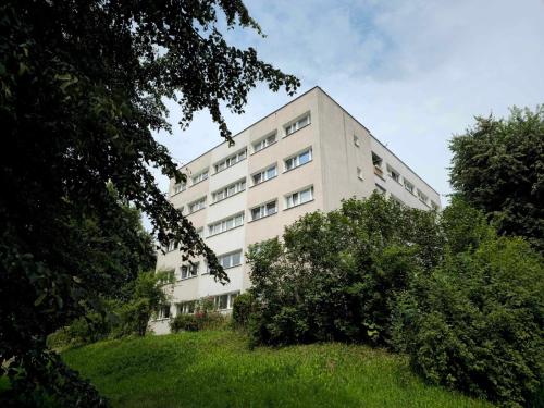 un edificio blanco alto con arbustos delante de él en Apartament w Centrum, en Jastrzębie-Zdrój