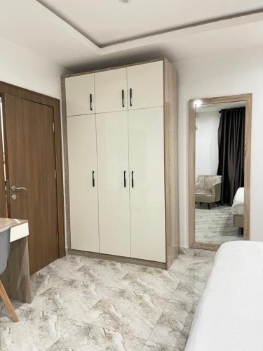 1oakapartments في أبوجا: غرفة نوم بها دواليب بيضاء ومرآة