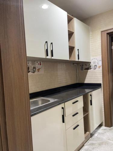 1oakapartments في أبوجا: مطبخ مع دواليب بيضاء ومغسلة