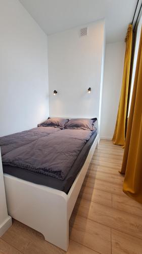 a bed in a room with a white wall at Mano erdvės in Anykščiai
