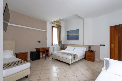 a bedroom with two beds and a desk and a window at Hotel Mantegna Stazione, MantegnaHotels in Mantova