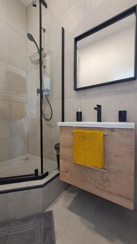 a bathroom with a shower and a sink with a yellow towel at Mano erdvės in Anykščiai