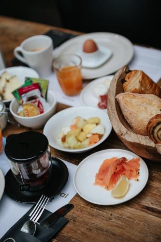 a wooden table with plates of food on it at La Merveilleuse by Infiniti hôtel in Dinant
