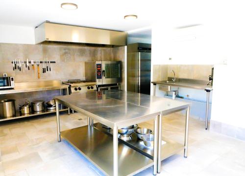 une grande cuisine avec une table en acier inoxydable dans l'établissement Le Domaine d'Arignac - La grande maison, à Arignac