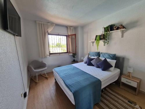 een slaapkamer met een bed met blauwe lakens en een raam bij Nice and cozy flat with pool next to the beach in Albir