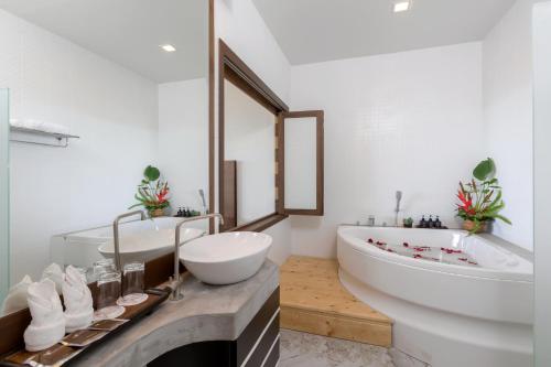 Secret Cliff Resort & Restaurant - SHA Plus في شاطئ كارون: حمام مع حوض أبيض كبير ومغسلة وحوض استحمام