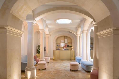Palazzo Artemide - VRetreats في سيراكوزا: غرفة كبيرة بها اعمدة بيضاء وكراسي زرقاء