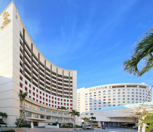 a hotel building with a palm tree in front of it at Loisir Hotel Naha in Naha