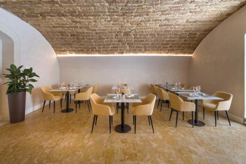 a restaurant with tables and chairs and a brick wall at Palazzo Artemide - VRetreats in Siracusa
