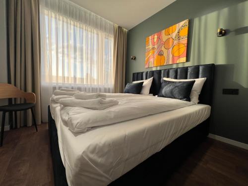 a bedroom with a large bed with white sheets at Luna Self Check-in Hotel Klaipeda in Klaipėda