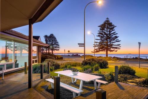 a picnic table on a deck with a view of the ocean at Frankies Beach House - A Breezy Esplanade Escape in Encounter Bay