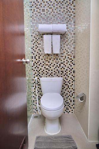 a bathroom with a toilet and a shower with towels at @Hom Semarang Simpang Lima in Semarang