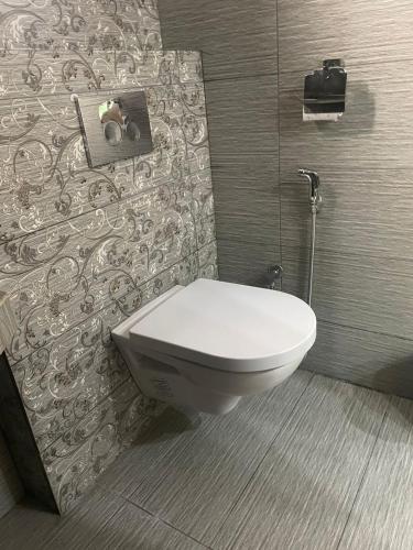 a white toilet in a bathroom with a wall at Grey Orchard Homestay - A Family Place in Lahore