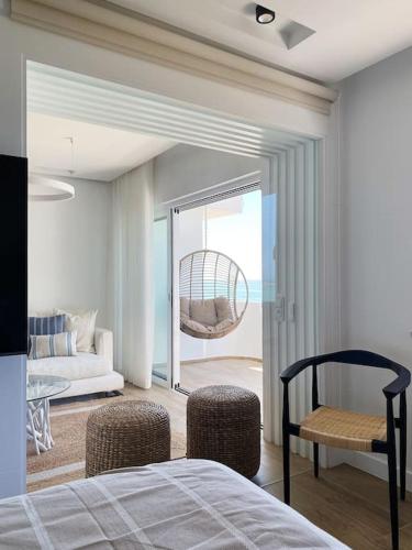 a bedroom with a bed and chairs and a balcony at Front Sea Apartment Albufeira in Albufeira