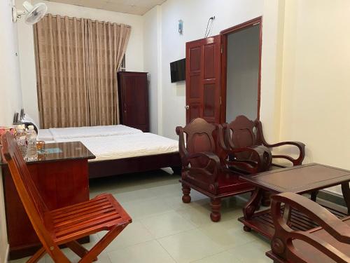 um quarto com uma cama, uma mesa e cadeiras em Hotel Cát Tường em La Gi