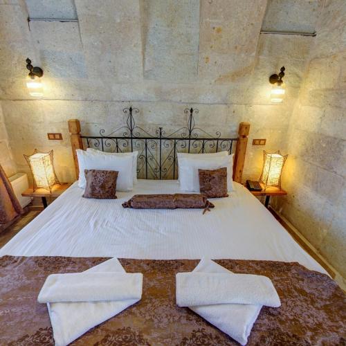 a bedroom with a large white bed with two towels at Roma Cave Suite in Goreme