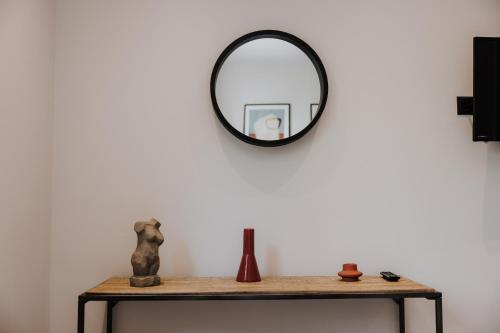 a mirror on a white wall next to a table at Pearl Apartel in Volos