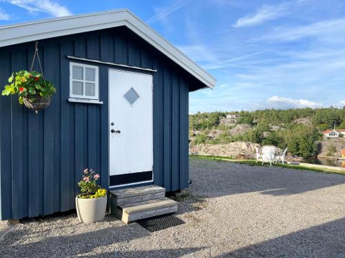 a blue shed with a white door and a window at Sea view chalet in Hjälteby