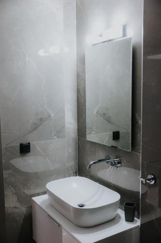 a bathroom with a white sink and a mirror at Pearl Apartel in Volos
