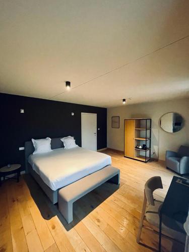 a bedroom with a large white bed and a chair at La Merveilleuse by Infiniti hôtel in Dinant