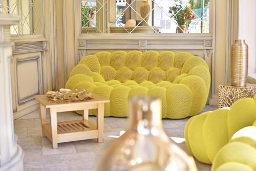 a living room with a yellow couch and a table at Hôtel Le Rocher in Calvi