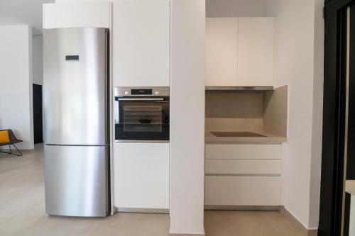 a stainless steel refrigerator in a white kitchen at Le chardonneret élégant in Kanali
