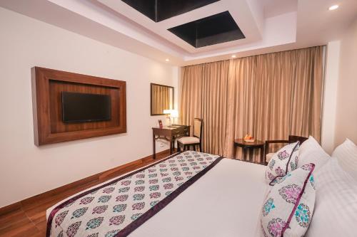 a hotel room with a bed and a television at Regenta Resort MARS Valley View Shoghi in Shimla