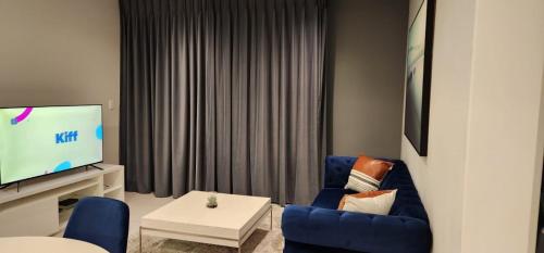 a living room with a blue chair and a tv at 2 bedrooms apartment in Johannesburg