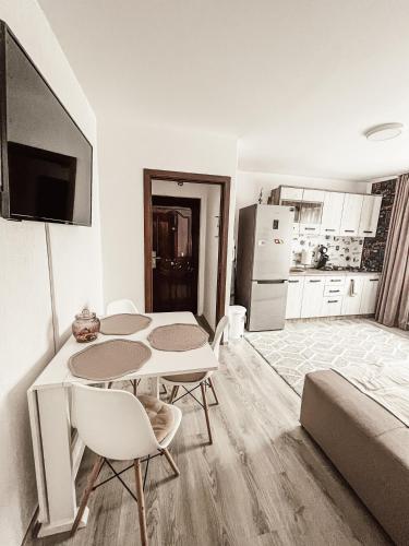 a living room with a table and chairs and a kitchen at Apartament One Divine - Zarnesti in Zărneşti