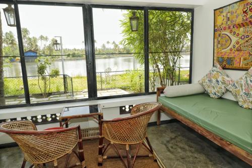 uma sala de estar com um sofá, cadeiras e janelas em Vala House em Cherai Beach