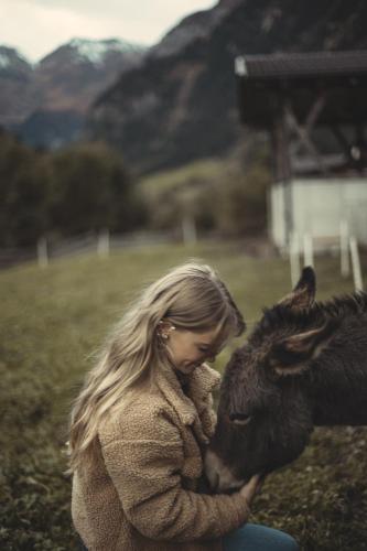 a woman is petting a donkey in a field at Ratschingser Kreuz Blasighof in Racines