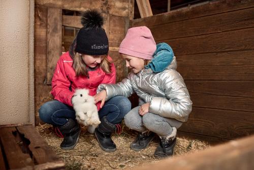 two children are playing with a lamb in a barn at Ratschingser Kreuz Blasighof in Racines