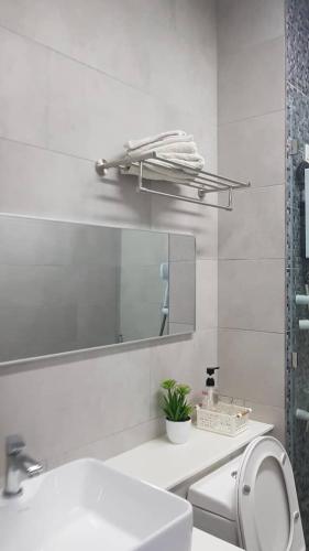 a white bathroom with a sink and a mirror at The Shore Ns Studio Suites Sea View in Kota Kinabalu